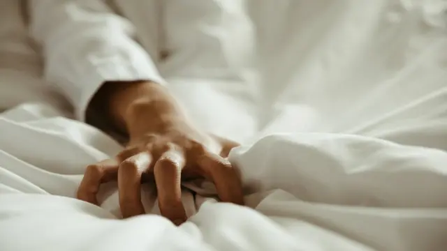 Mano sobre la sábana