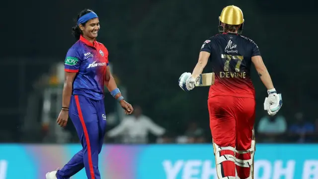 दिल्ली कैपिटल की शिखा पांडेय आरसीबी की सोफ़ी डेवाइन का विकेट लेने के बाद