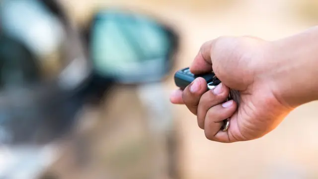 Mano sosteniendo llave inalámbrica para abrir el auto.