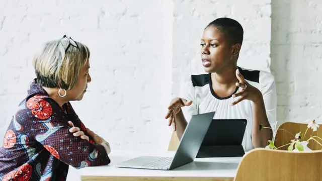 Duas mulheres conversando sentadas à mesa