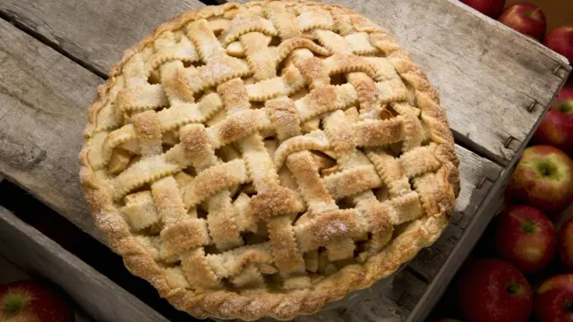 Яблочный пирог с плетеной крышкой на деревянном столе