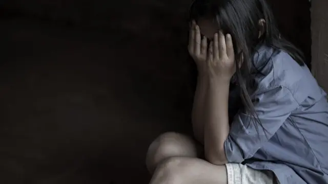 Une fille assise se couvre le visage de ses mains en signe de désespoir.