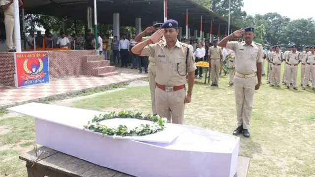 ताबूत के सामने सलामी देते पुलिसकर्मी