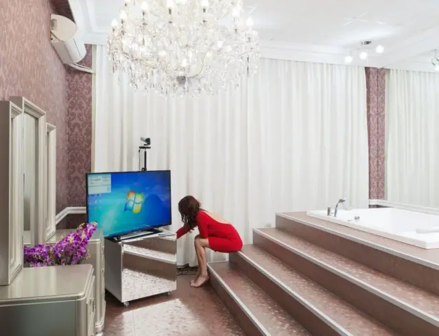 Một người mẫu chuẩn bị ghi hình với bối cảnh bồn tắm, được hoàn thiện bởi một chùm đèn lớn