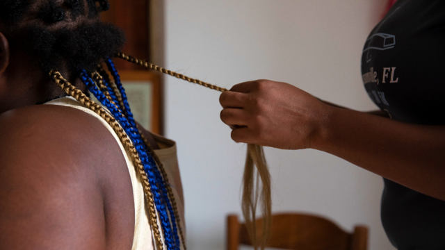 Une Nigériane tresse les cheveux d'une autre femme dans un refuge en Sicile après avoir échappé à des réseaux de trafiquants