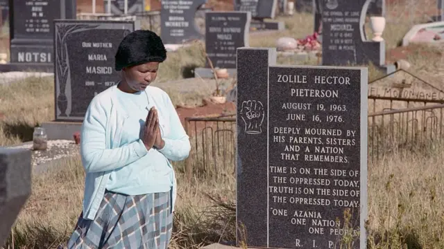 La mère d'Hector Pieterson, l'une des premières victimes des émeutes de 1976 à Soweto, prie sur sa tombe.