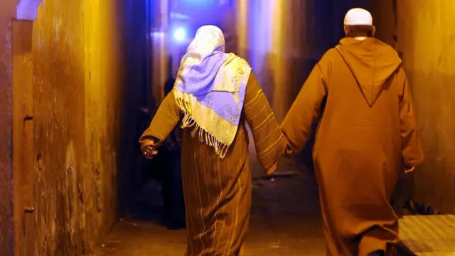 Man and woman hold hands dey waka for night