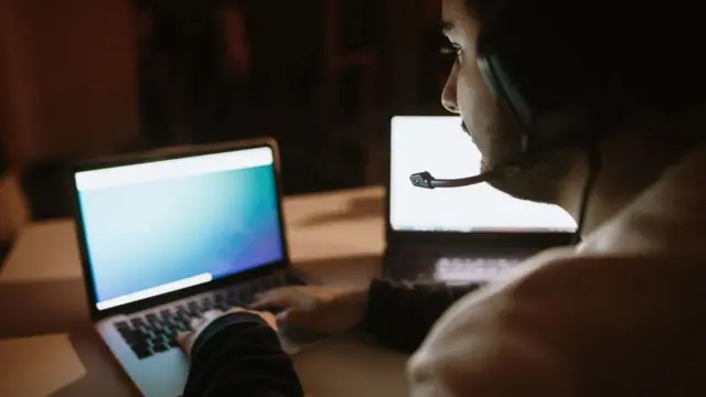 Un hombre trabajando en dos computadoras.