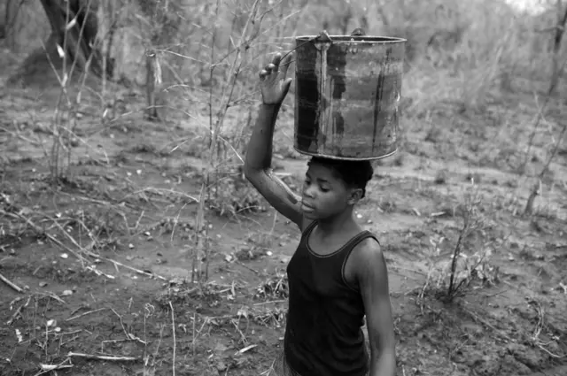 Josefina carries water home from the Rio Naranja in a bucket.