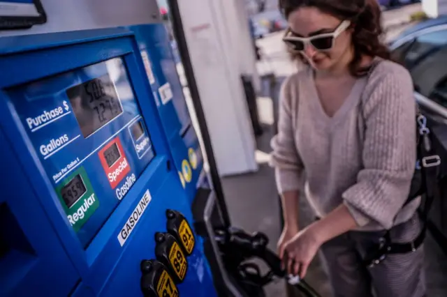 Mujer poniendo gasolina a su coche en California.