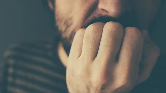 Hombre mordiéndose las uñas.