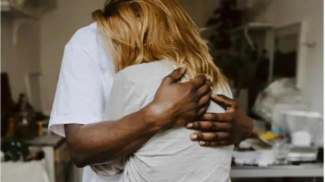 Homem negro abraça mulher branca