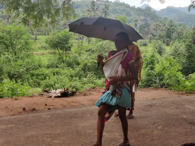 చండి బిడ్డతో నడిచి వెళ్తున్న తల్లి