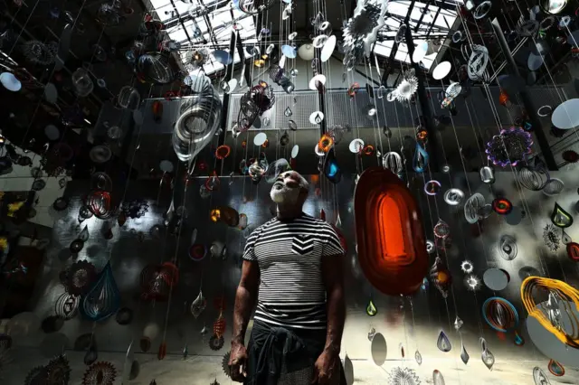 Artist Nick Cave poses underneath suspended objects