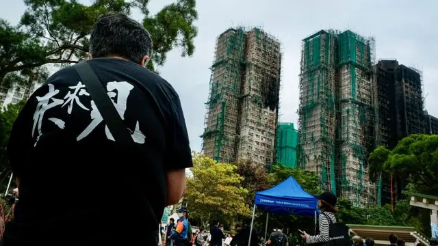 Relatives of firefighter Ho Wai-ho, who died in the deadly fire at the Wang Fuk Court residential estate in Tai Po district, hold his portrait during his burial at Gallant Garden in Hong Kong on December 19, 2025. 