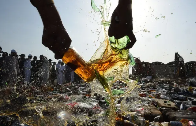 شخص يحطم زجاجات من الكحول