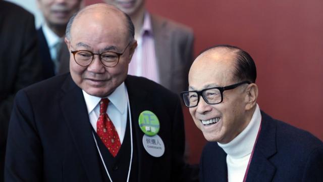 Billionaire Li Ka-shing, chairman of CK Hutchison Holdings Ltd. and Cheung Kong Property Holdings Ltd., right, greets Woo Kwok-hing, a candidate for Hong Kong's chief executive and retired judge, as he arrives at a polling station for the chief executive election in Hong Kong, China, on Sunday, March 26, 2017.
