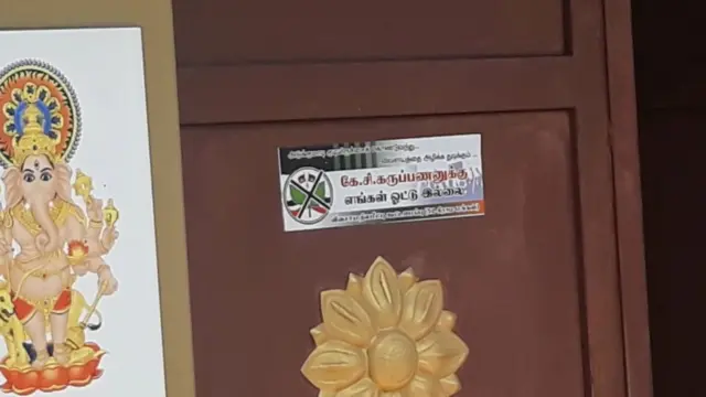 வீட்டுக் கதவில் அமைச்சருக்கு வாக்கு இல்லை என ஒட்டப்பட்டிருக்கும் ஸ்டிக்கர்