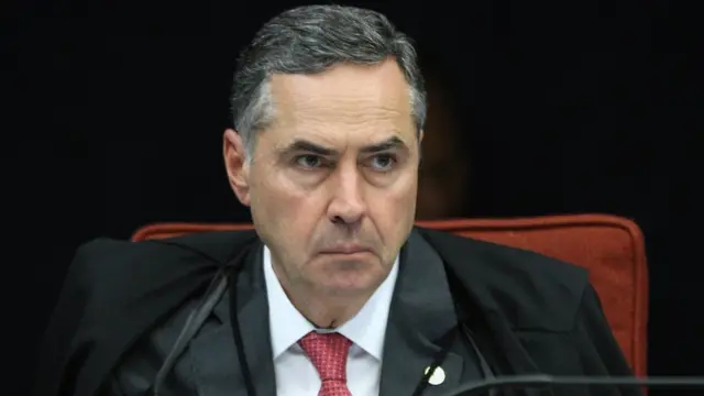 Luís Roberto Barroso sentado na cadeira do plenário, olhando para frente com ar compenetrado