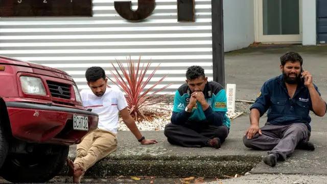Grieving members of the public sit on the ground after the shooting at Al Noor mosque.