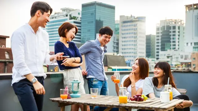 Friends having fun and greetings together starting a rooftop party in Seoul - Hongdae district.