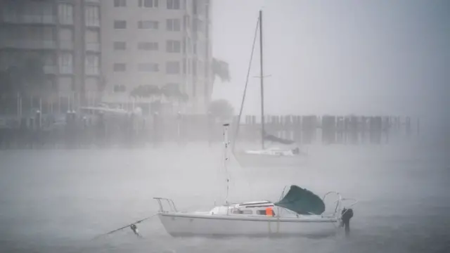 Barco no meioblaze de apostasuma marina, pouco visível devido à neblina causada pelo vento forte e a chuva