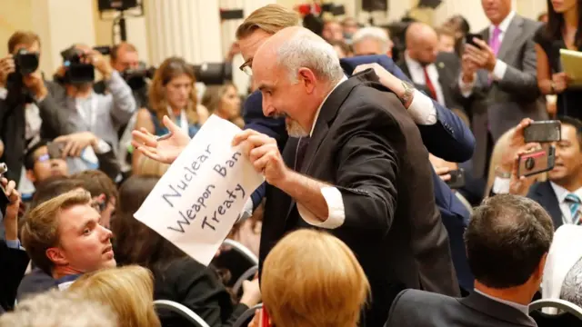Periodista con un letrero que dice "Tratado de prohibición de armas nucleares".