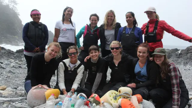 Mujeres participantes de EXXpedition en una playa frente a una pila de plástico que recogieron