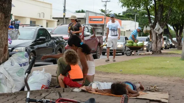 Imigrantes venezuelanos pedindo ajuda no semáforo