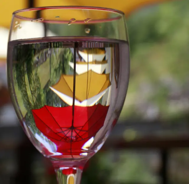 Sombrillas reflejadas en una copa de vino.