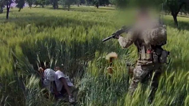 Solder pointing gun at person lying on the ground