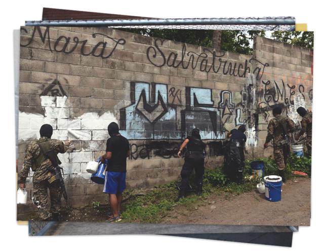 Un grupo de funcionarios tapa un grafiti de la MS-13 con pintura en un poblado de El Salvador