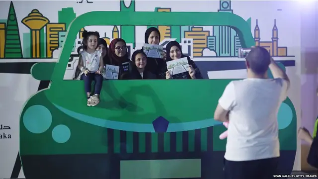 SAUDI ARABIA - JUNE 22: Teenaged girls pose behind a pretend car while they old up certificates for completing an outdoor educational driving event for women