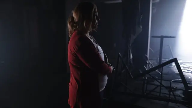 Scene of The Endless Night shows a woman looking at the scorched nightclub