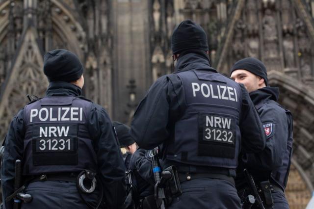 Tres policías alemanes de espaldas conversando