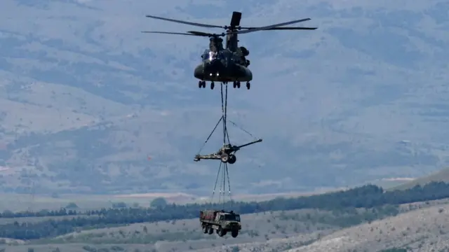 Вертолет перевозит гаубицу и грузовик