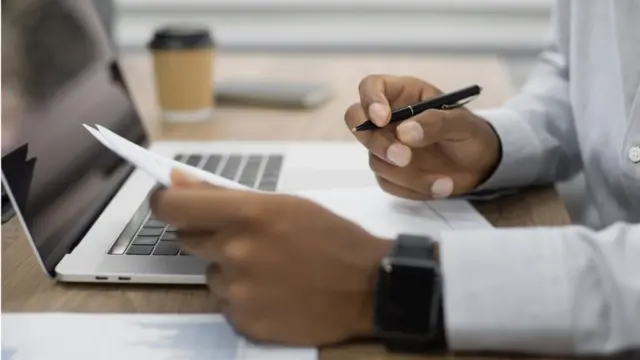 Umugabo uri gukorera ku rupapuro na mudasobwa