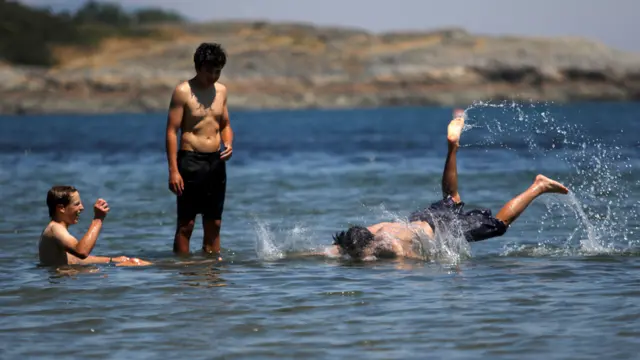 سكان محليون يبحثون عن أفضل الطرق لمجابهة الحر اللاهف الناتج عن "قبة حرارية" تقبع فوق إقليمي بريتيش كولومبيا وألبرتا الكنديين، وذلك بالسباحة في شاطئ ويلوز بيتش