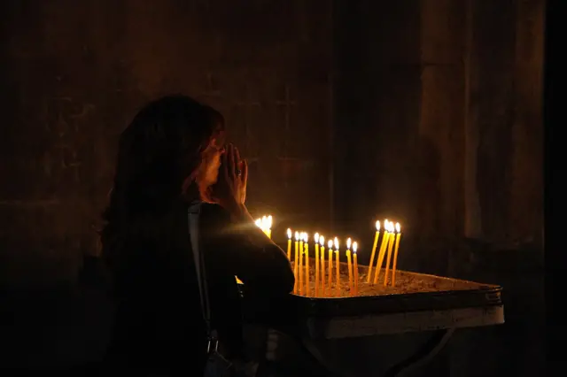 Žena se moli nakon što je zapalila sveću unutar manastira Gandzasar.