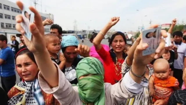 Para pengunjuk rasa Uighur menunjukkan kartu identitas dari kerabat yang ditahan dalam sebuah demonstrasi pada 2009.