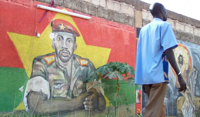Man walking by Thomas Sankara mural