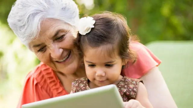 Una abuela con su nieta mirando una tableta.