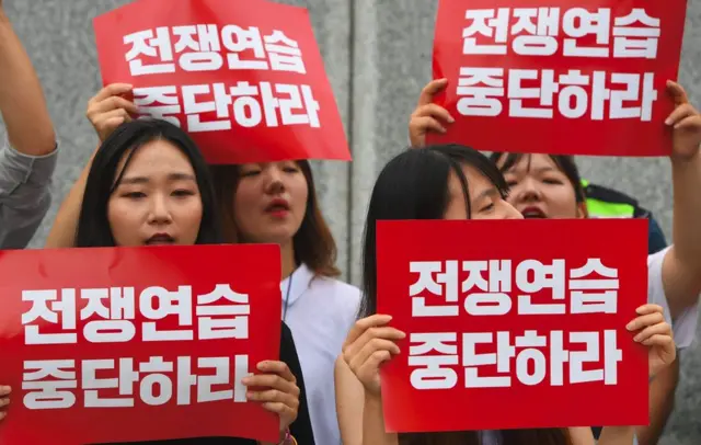 Manifestantes surcoreanos con letreros que leen: "Detengan los ejercicios de guerra" cerca de la embajada de EE.UU. en Seúl
