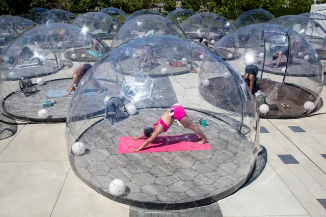 People practise yoga in individual transparent domes