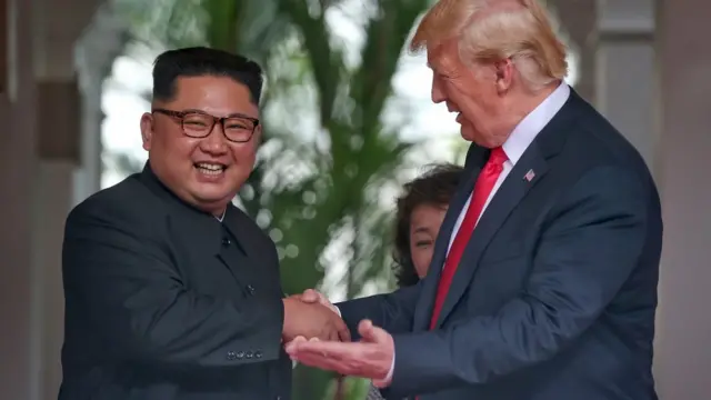 Kim Jong-un e Donald Trump se cumprimentam e sorriem