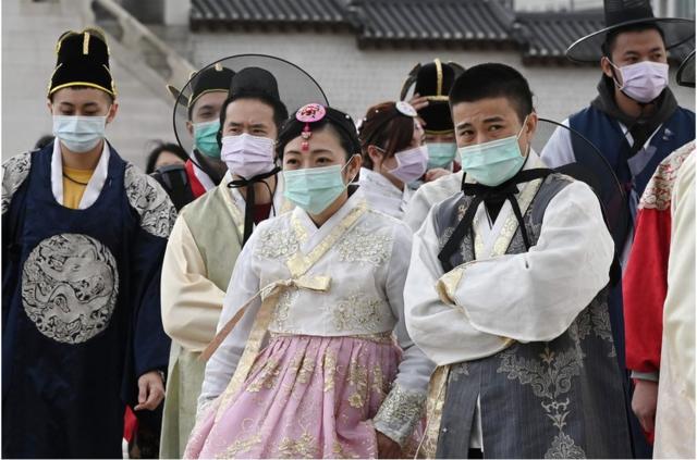 2020年1月30日，身穿传统韩服的游客在前往首尔景福宫时戴上口罩。