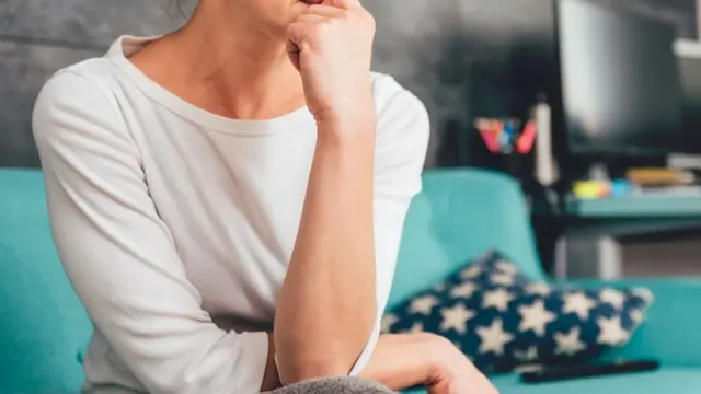 A cropped woman sits in concerned position