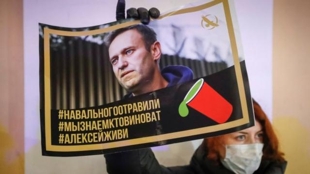 Protester holds poster with hashtags "Navalny was poisoned", "We know who's to blame" and "Alexei, stay alive"