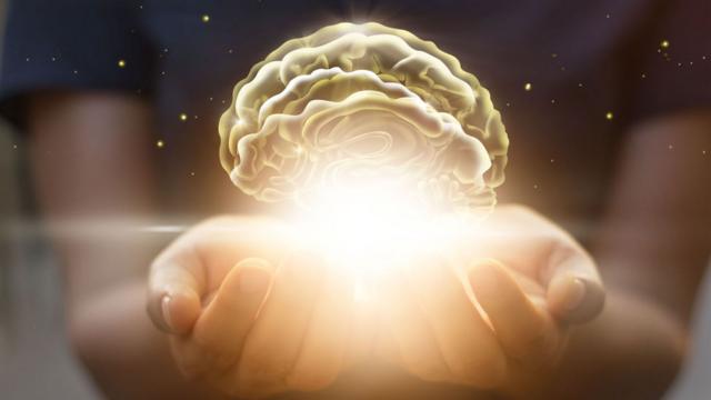 Ilustración de un cerebro iluminado sobre las manos de una mujer