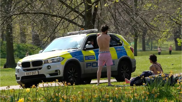 پلیس با دو مرد جوان که روز شنبه در پارک سن جیمز لندن آفتاب می گرفتند صحبت می کند
